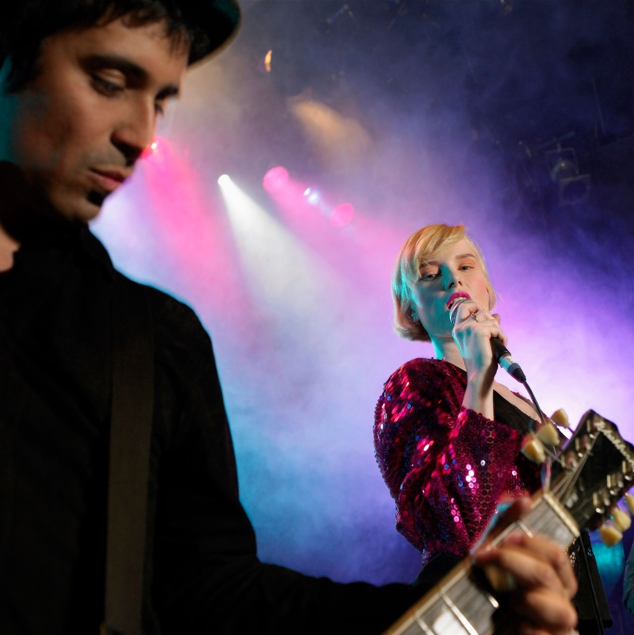 Groupes-musique-amateurs Guitariste et chanteuse portant une robe à sequins rose et tenant un micro à la main