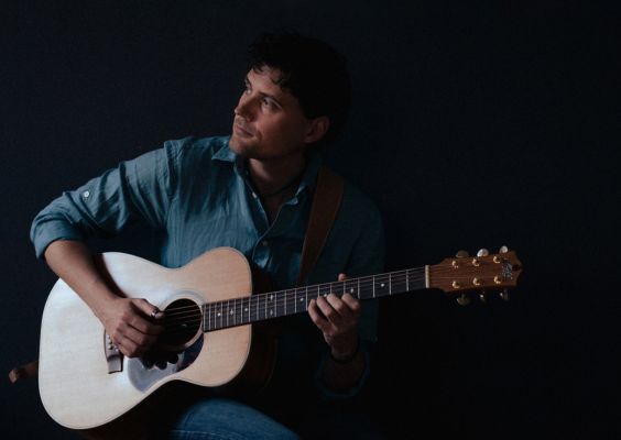 Hervé-Amiot Hervé Amiot jouant de la guitare acoustique en chemise bleue, ambiance sombre et intimiste
