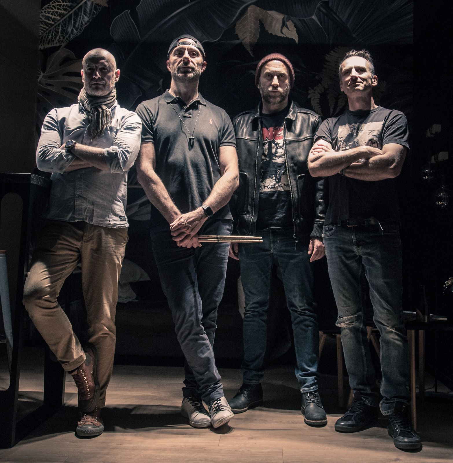 Photo en noir et blanc du groupe Léopoldine, quatre musiciens souriants posant avec leurs instruments dans une ambiance décontractée